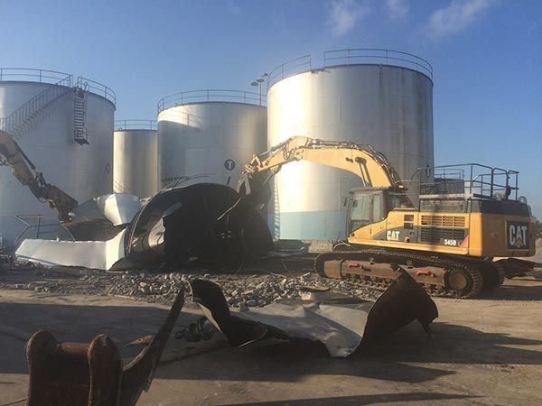 A large tank is being demolished by a cat excavator.