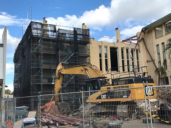 A man in an orange shirt is working on a building
