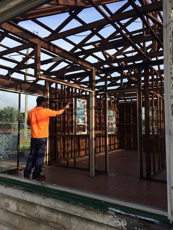 A man in an orange shirt is working on a building