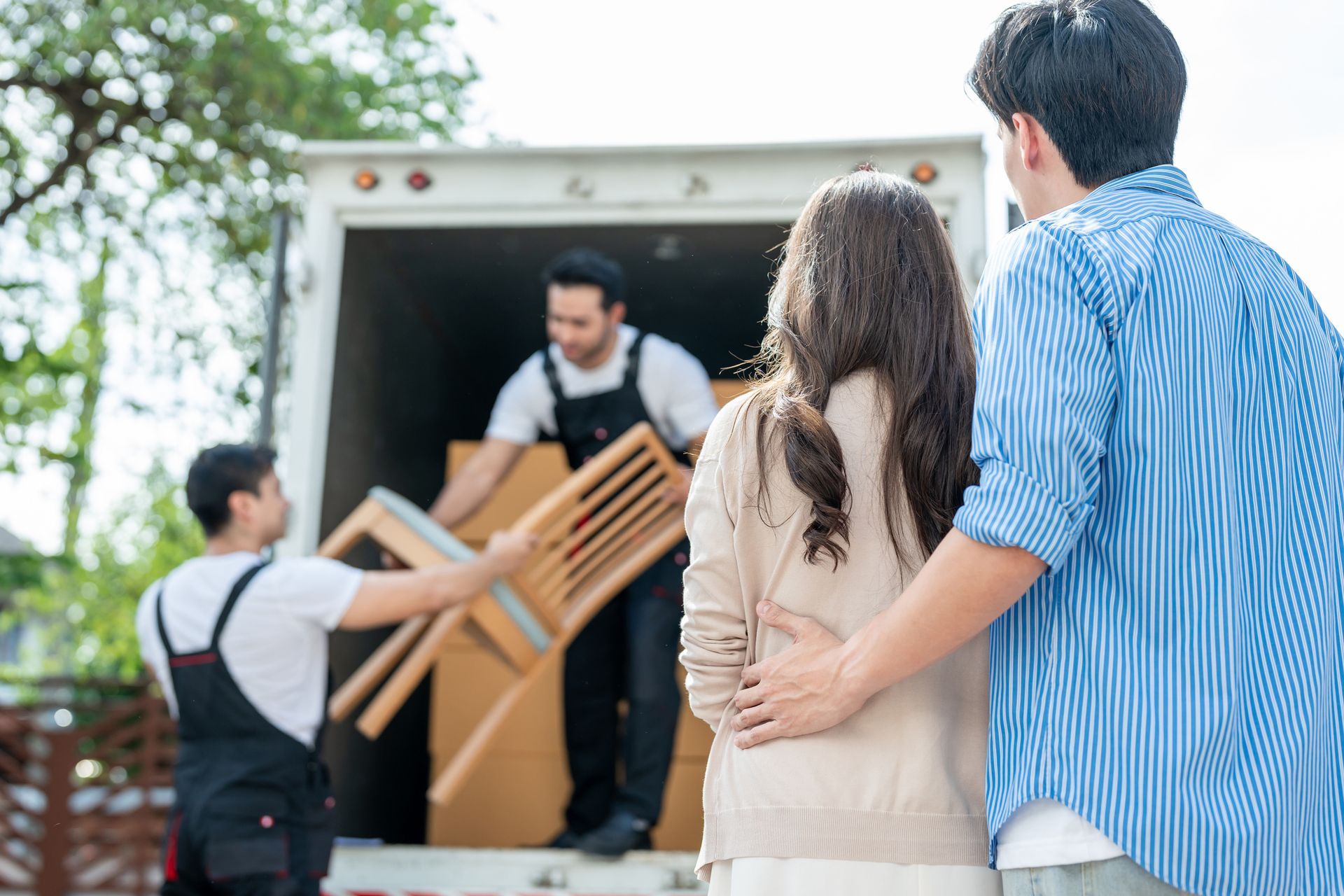 A man and a woman are standing in front of a moving truck.