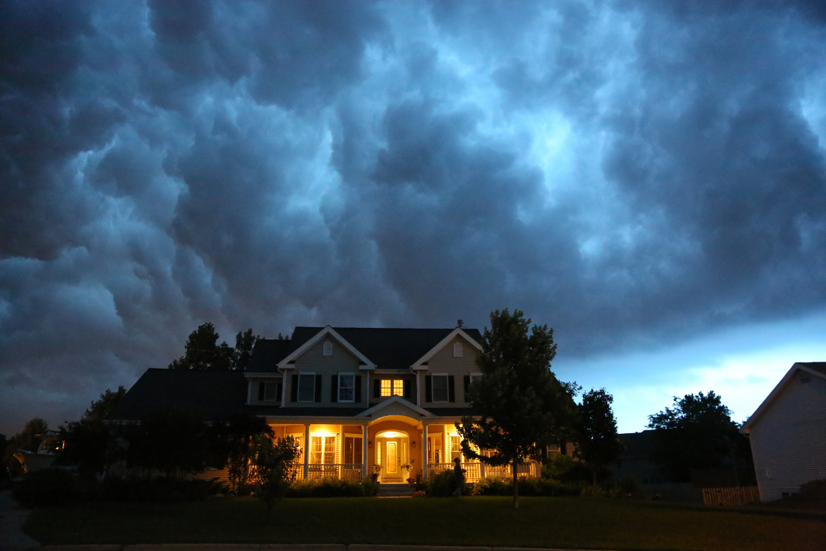 A house is lit up in front of a stormy sky