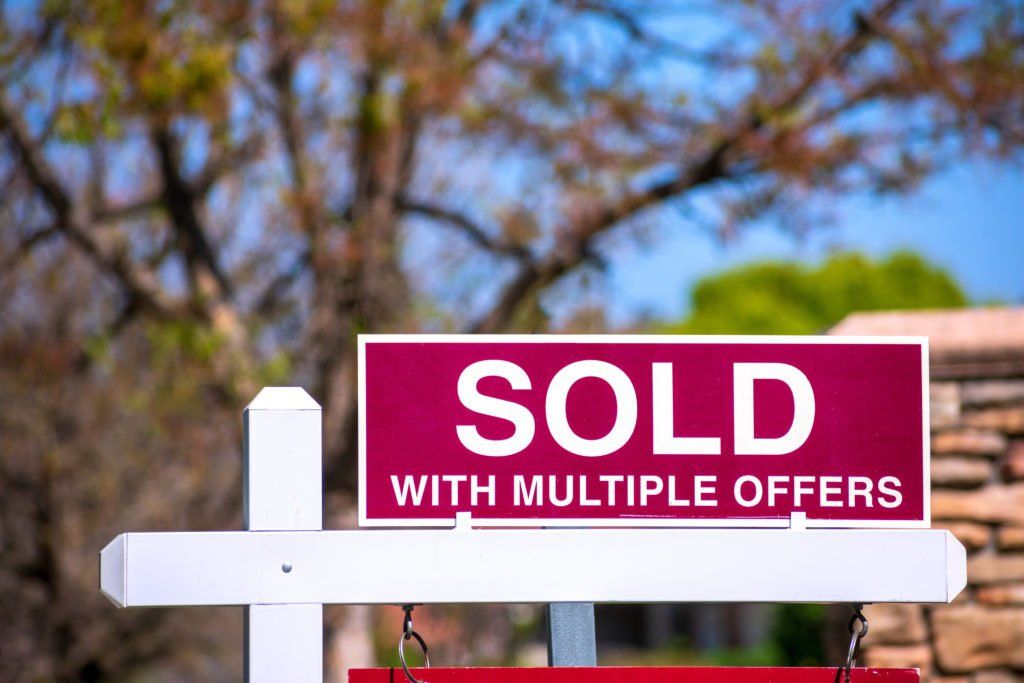 A red and white sold sign with multiple offers
