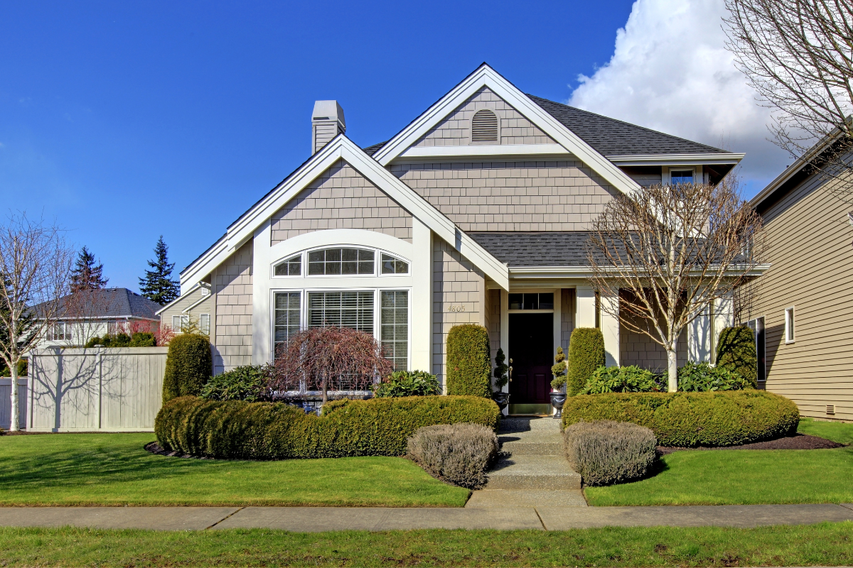 A house with a lot of windows and bushes in front of it