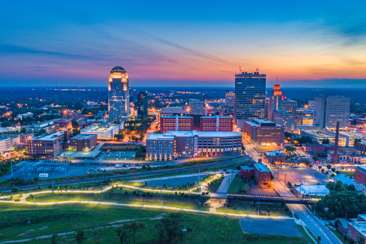 An aerial view of a city at night with a sunset in the background