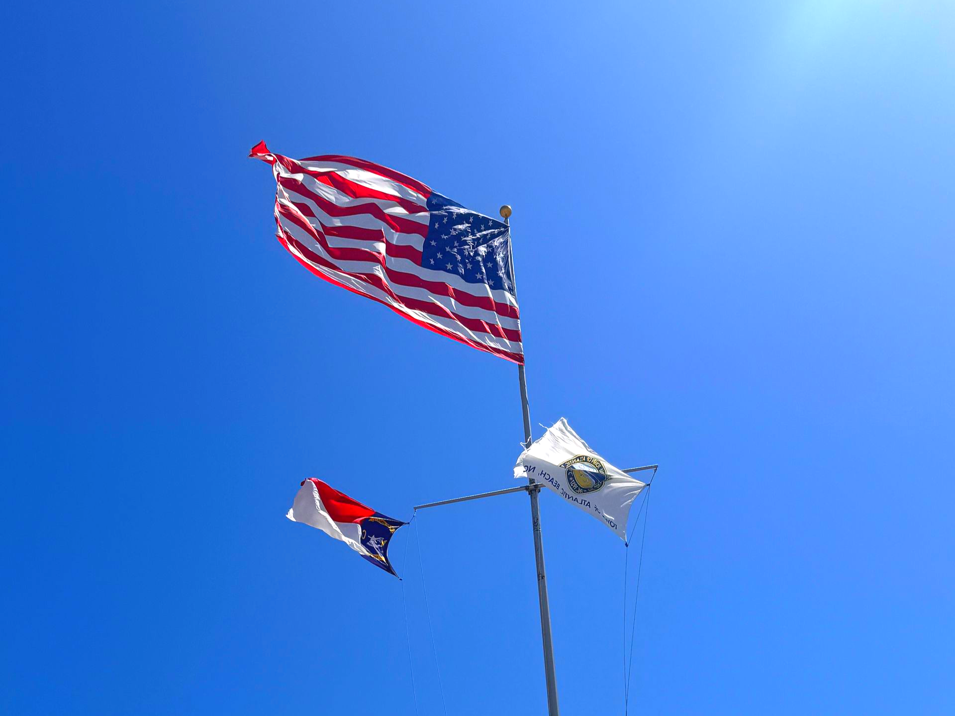Three flags blowing in the wind in Atlantic Beach NC near the water tower and the welcome sign