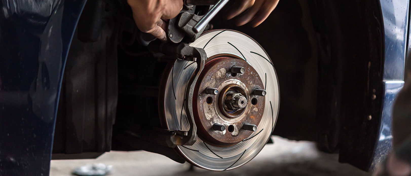 a man is fixing a brake disc on a car with a wrench .