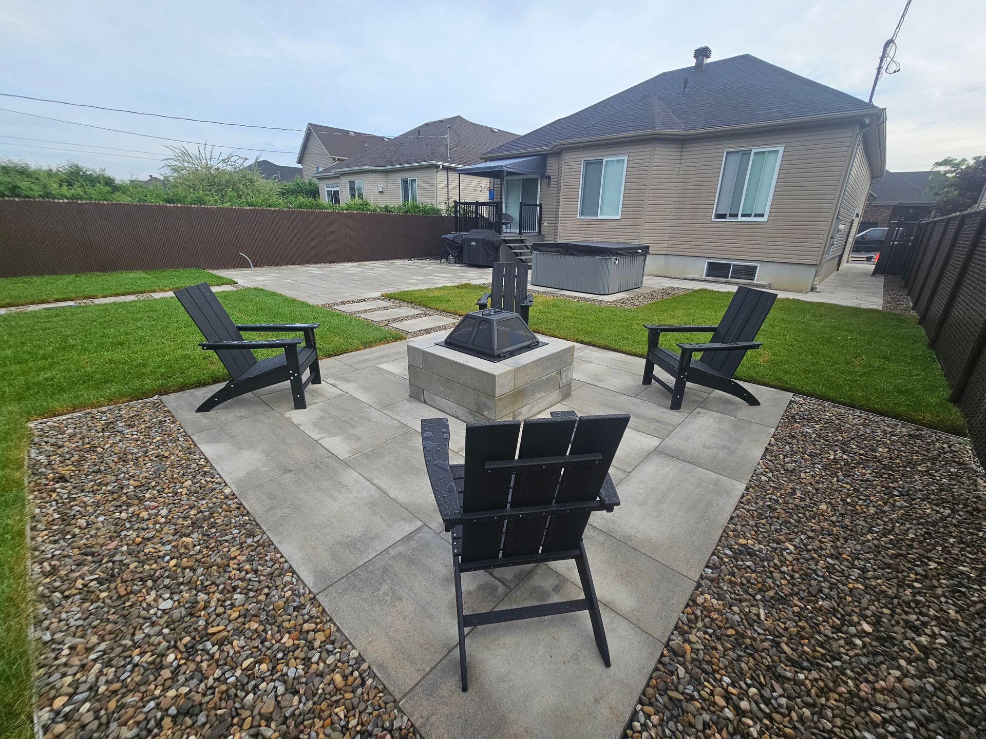 Trois chaises sont assises autour d'un foyer dans une cour arrière.