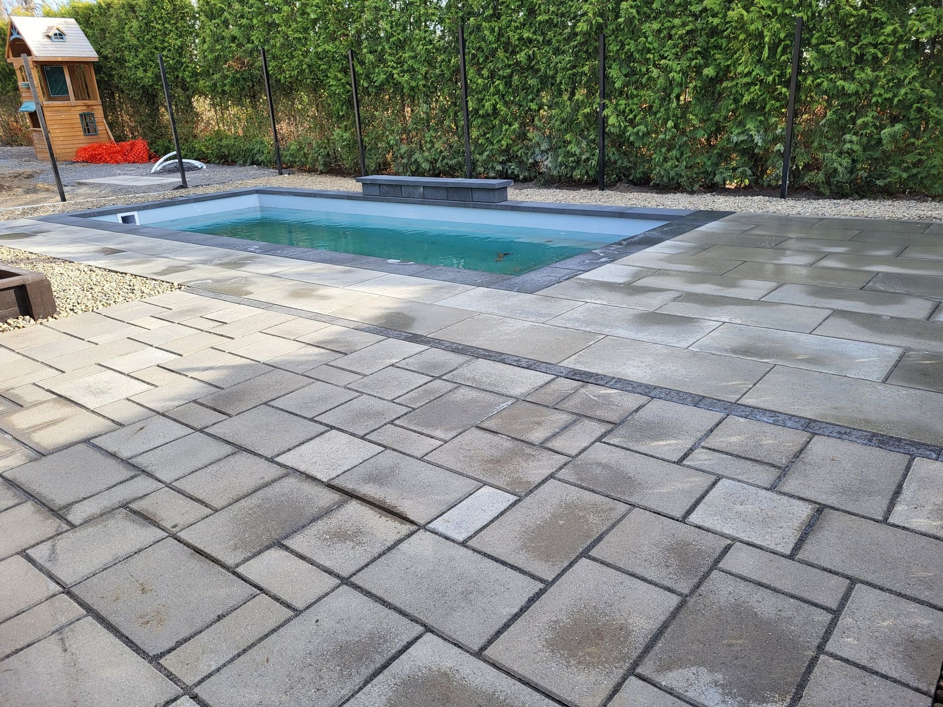 Une petite piscine est entourée d'un patio en briques.