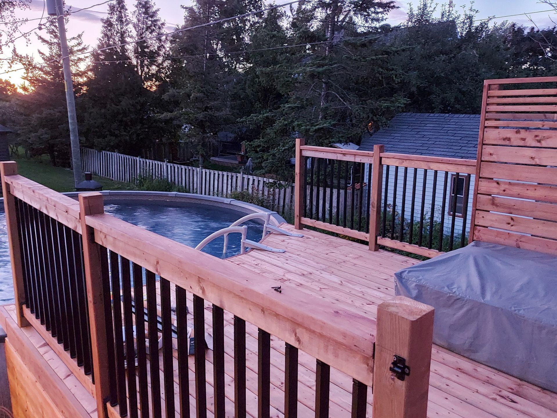 Une terrasse en bois avec un jacuzzi et une piscine en arrière-plan