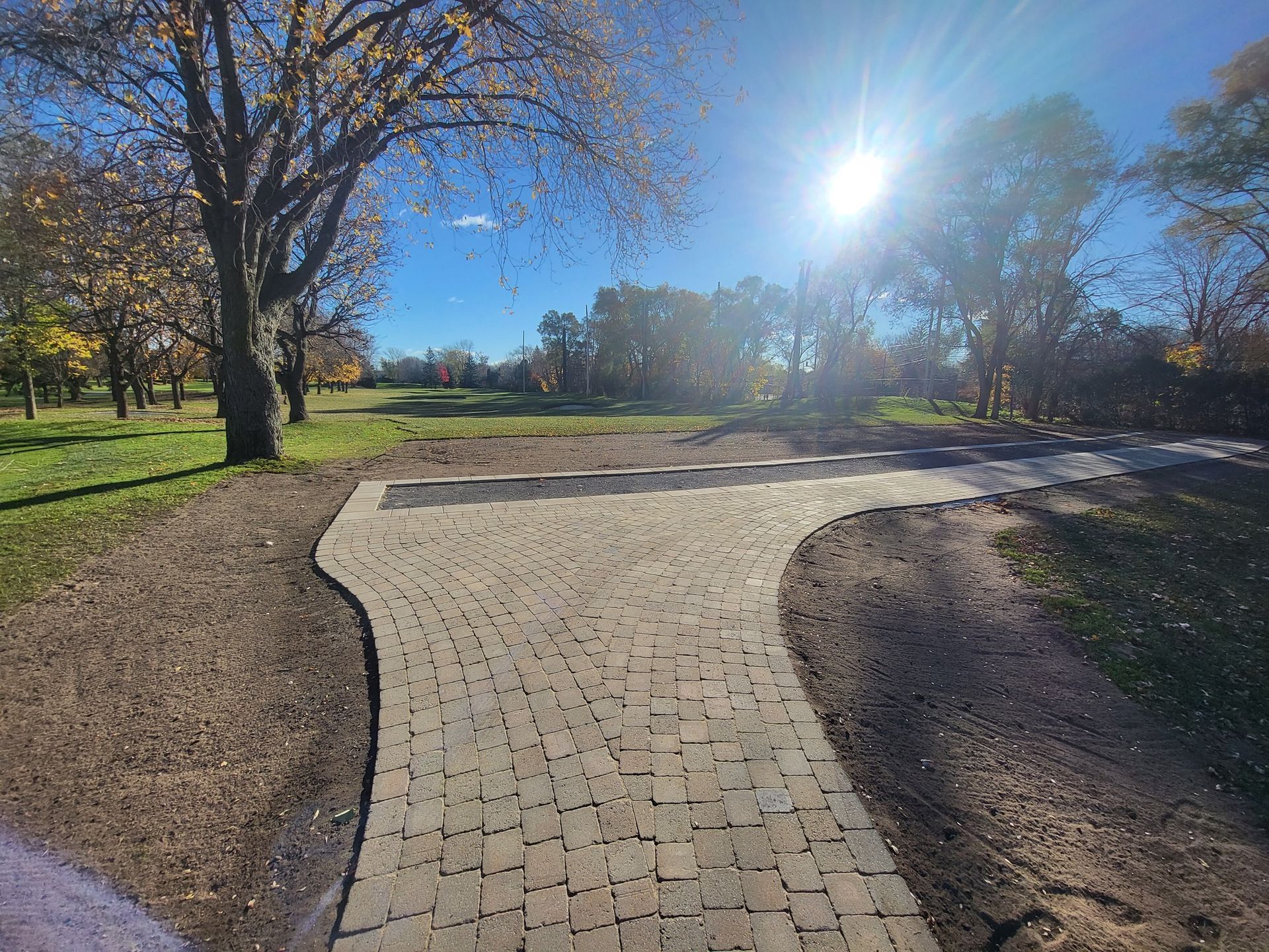 Une allée en briques menant à un parc par une journée ensoleillée.