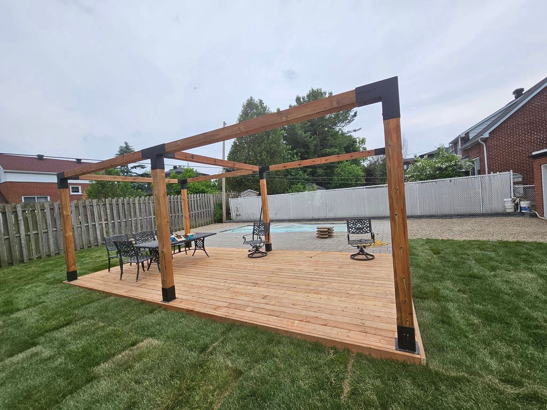 Une terrasse en bois dans une cour arrière à côté d'une piscine.