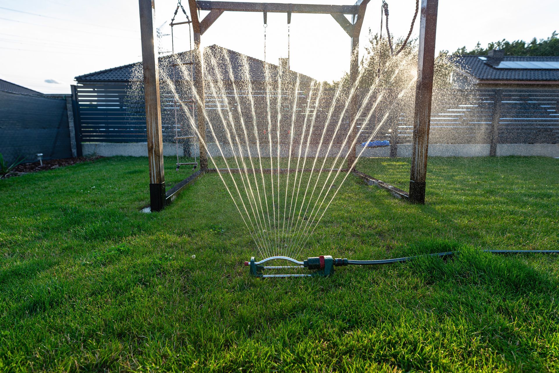 Un arroseur de pelouse pulvérise de l'eau sur une pelouse verte luxuriante.