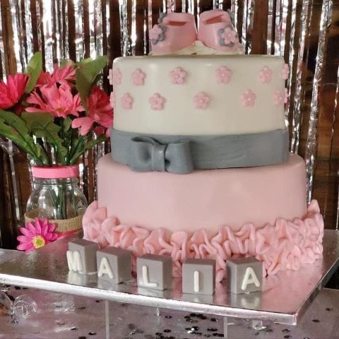 A pink and white cake with the name malia on it