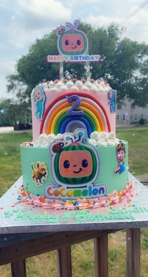A cake with a rainbow on top of it is on a table.