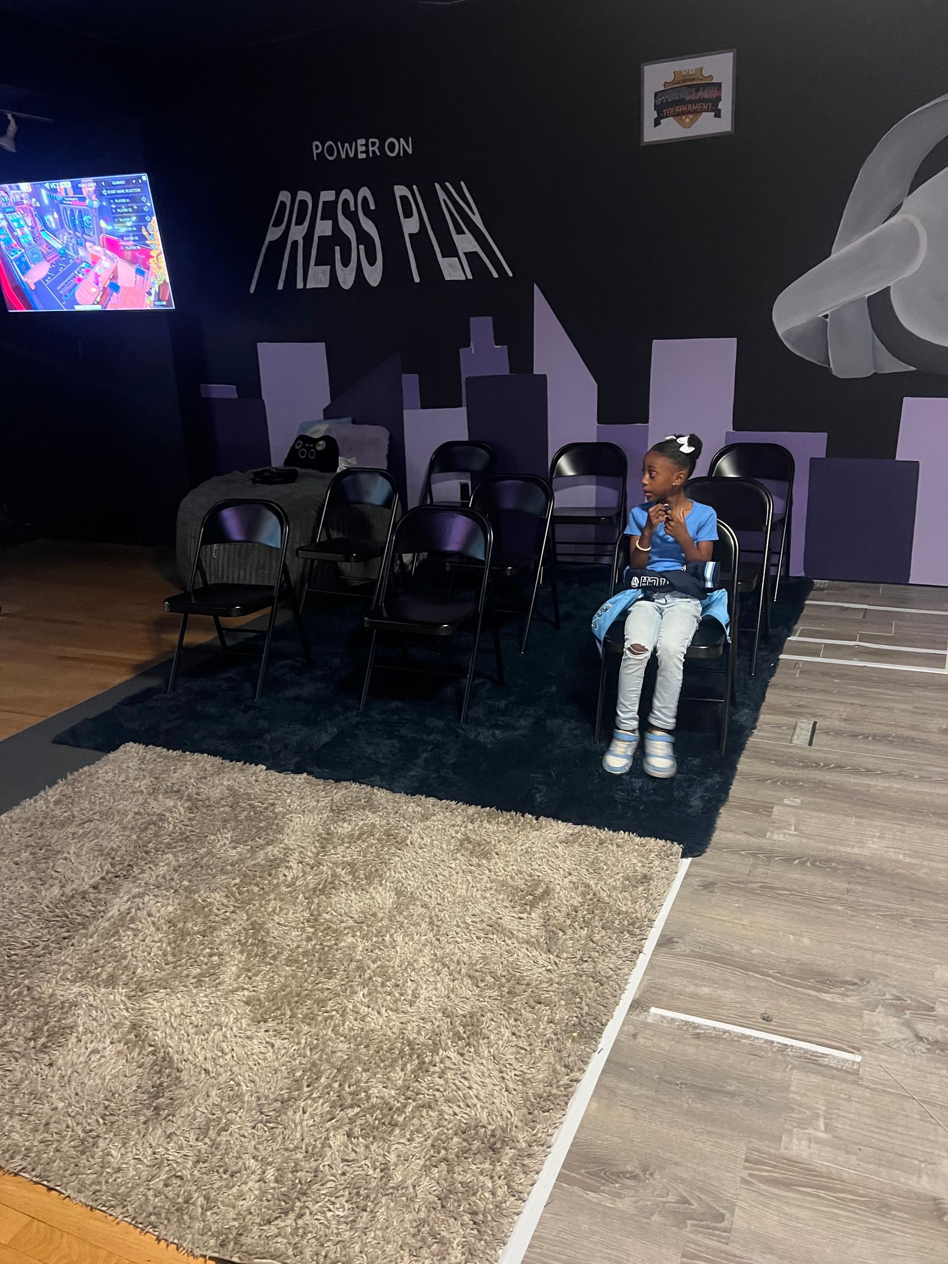 Girl seated in front of chairs, inside a room with a 