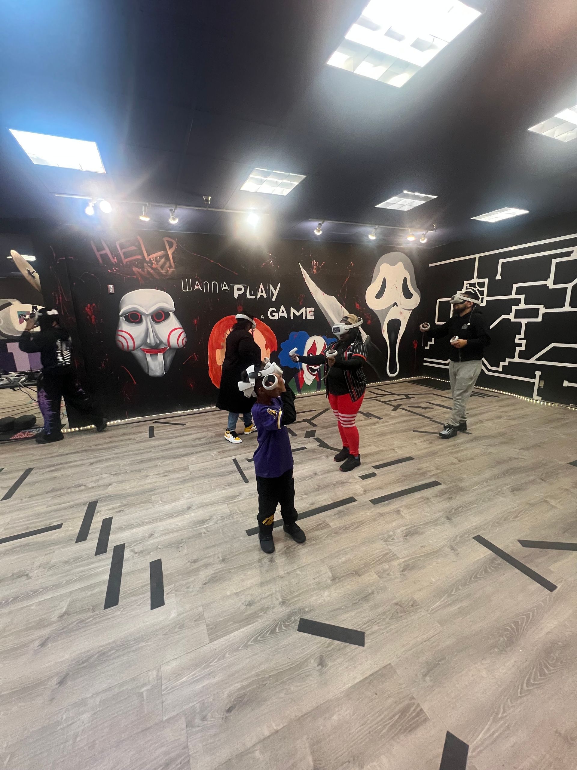 People in a room with Saw-themed decorations, including a Billy the Puppet image, holding a ball.