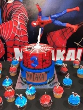 A spiderman cake with cupcakes around it