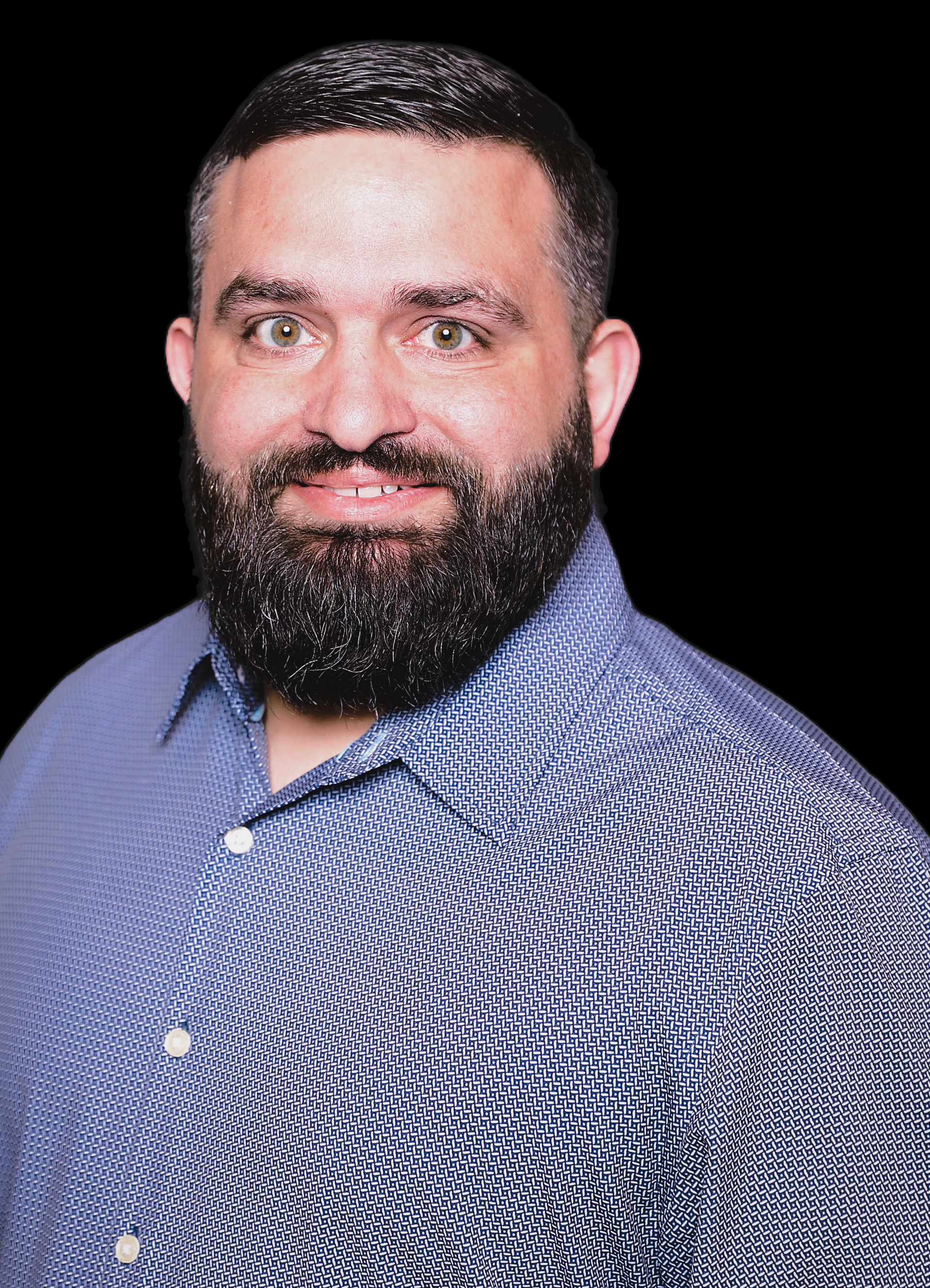 A man with a beard is wearing a blue shirt and smiling.