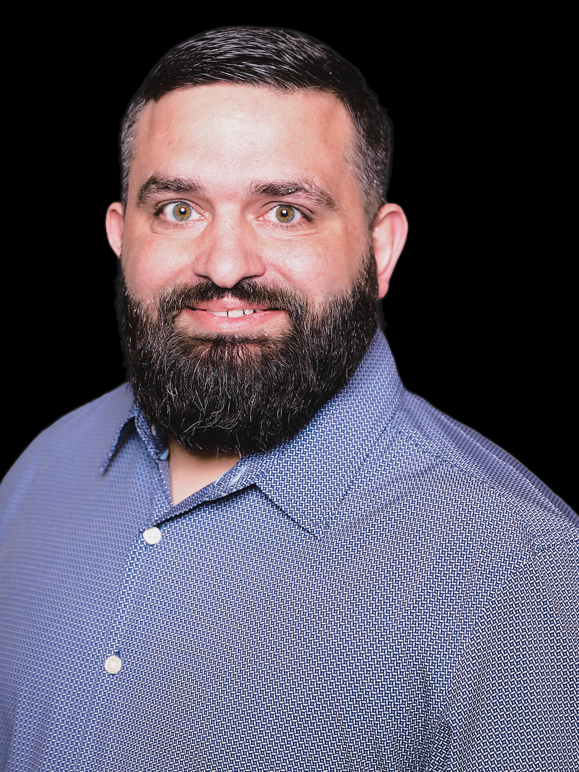 A man with a beard is wearing a blue shirt and smiling.