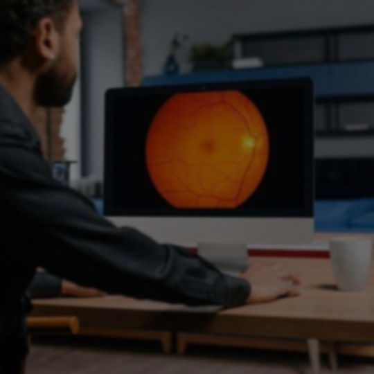 A man is looking at a computer screen with an orange circle on it.