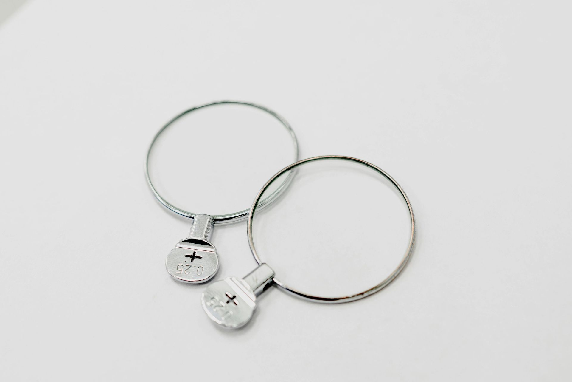A pair of silver hoop earrings are sitting on a white surface.