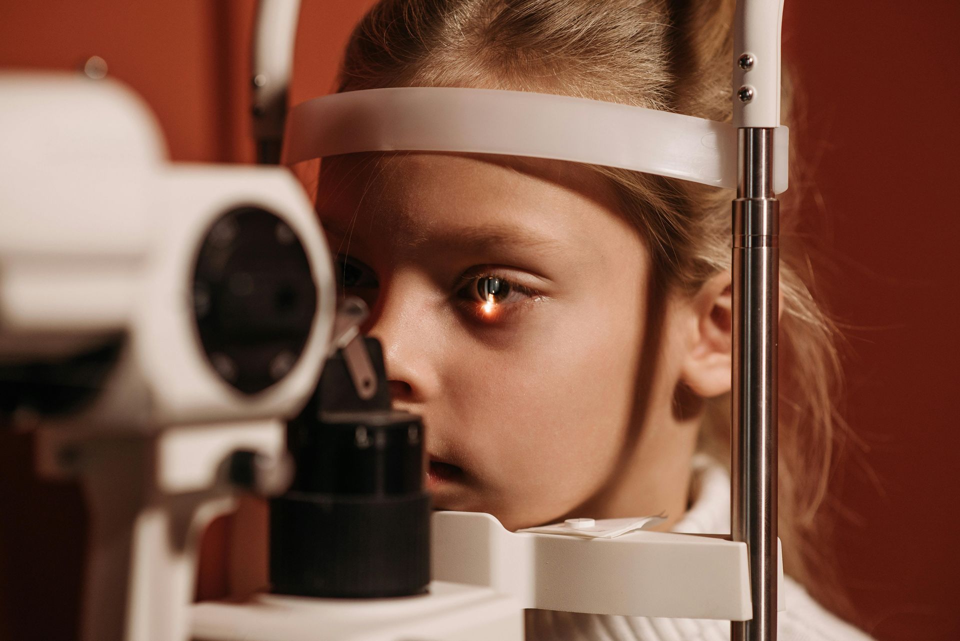 A little girl is getting her eyes examined by an ophthalmologist.