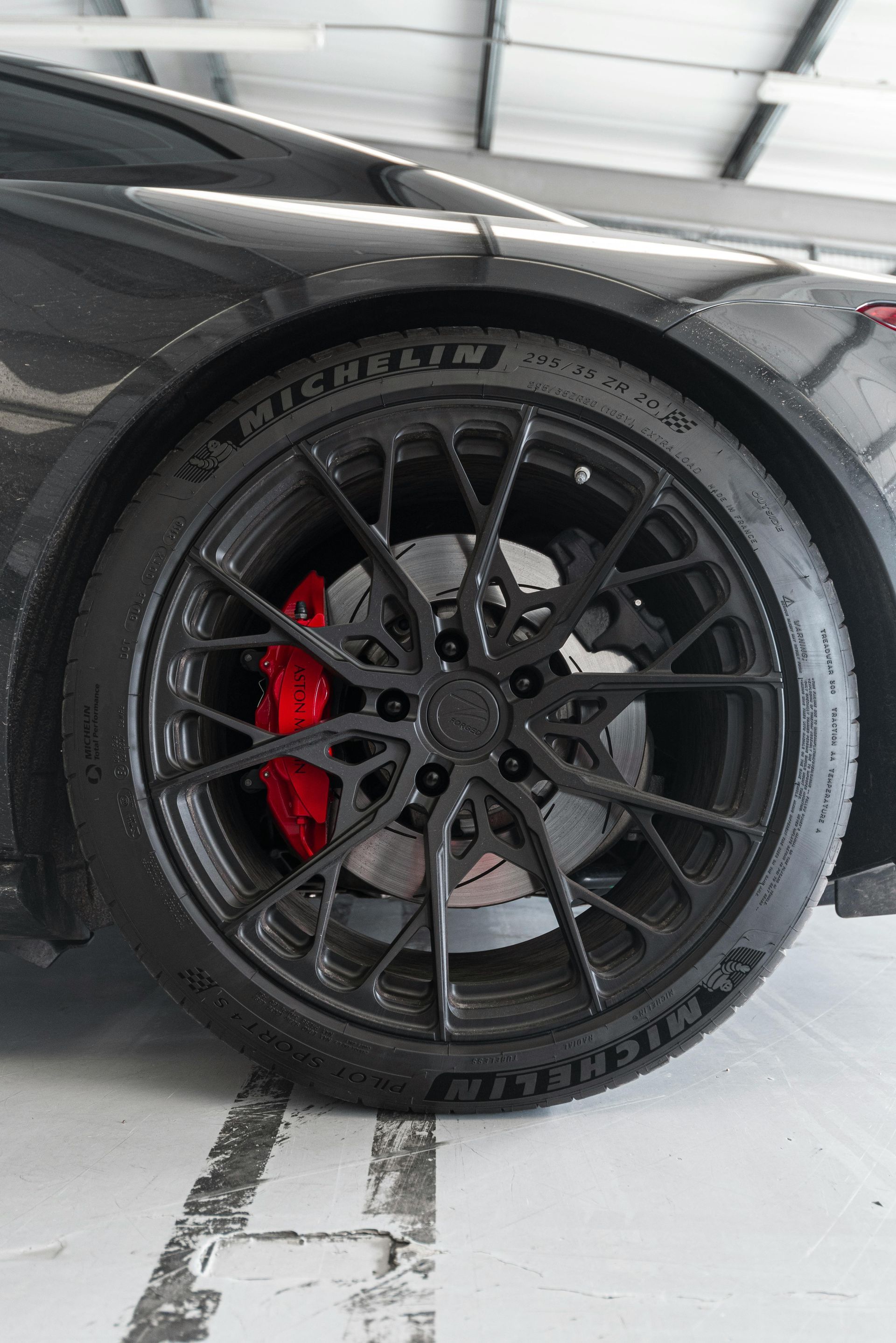 A close up of a car wheel with a red brake caliper.