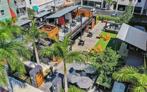 An aerial view of a restaurant surrounded by palm trees and umbrellas.
