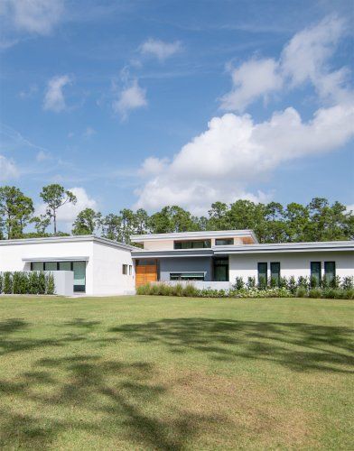 A large white house is sitting on top of a lush green field.