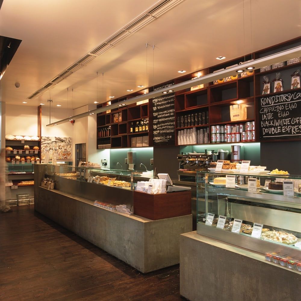 a bakery with a display counter of baked goods, shelves of bakery items, and espresso machines.