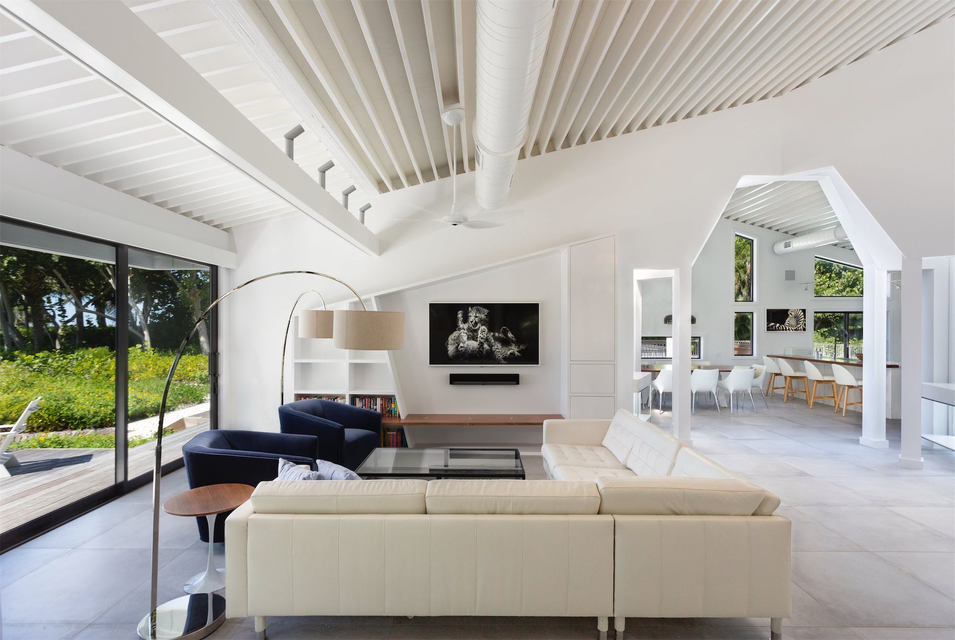 a white room with large windows and with a table, storage cabinets, and a lamp