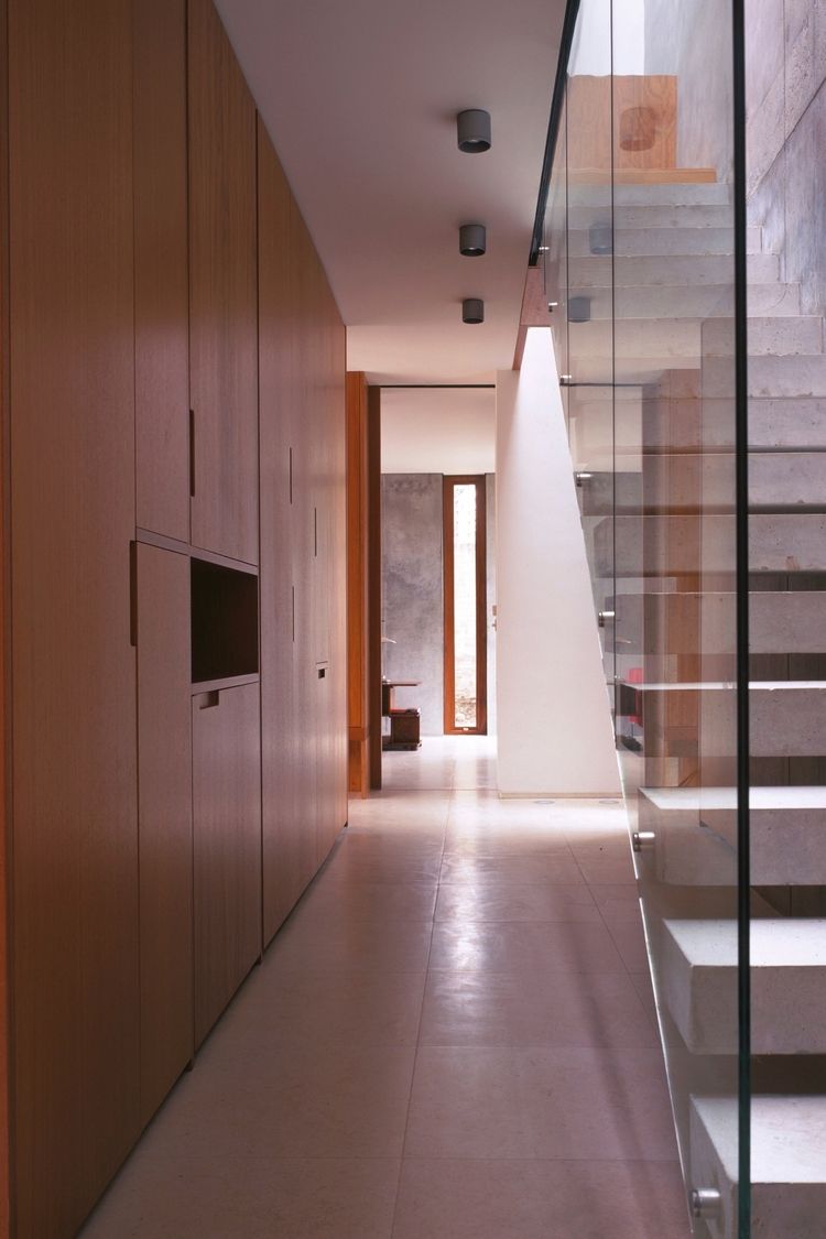 a hallway leading to a staircase with a glass railing