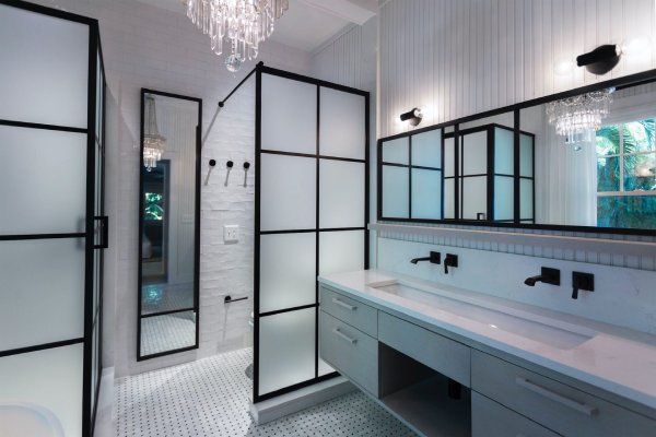 A bathroom with a walk in shower , sink and mirrors.