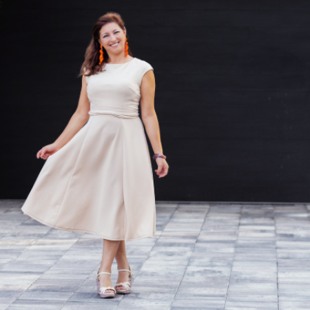 A woman in a white dress is standing on a sidewalk
