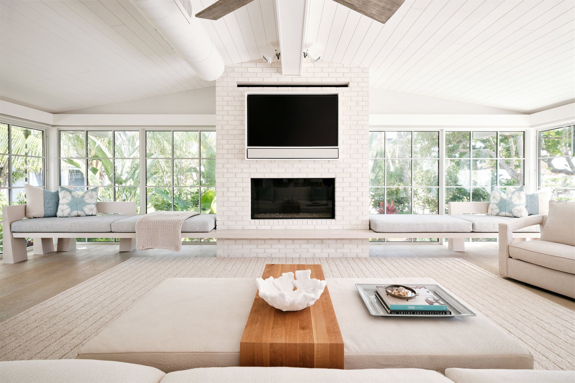 a living room with a fireplace and a flat screen tv with a picture window on each side