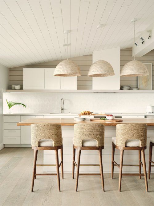 A kitchen with white cabinets and wooden stools