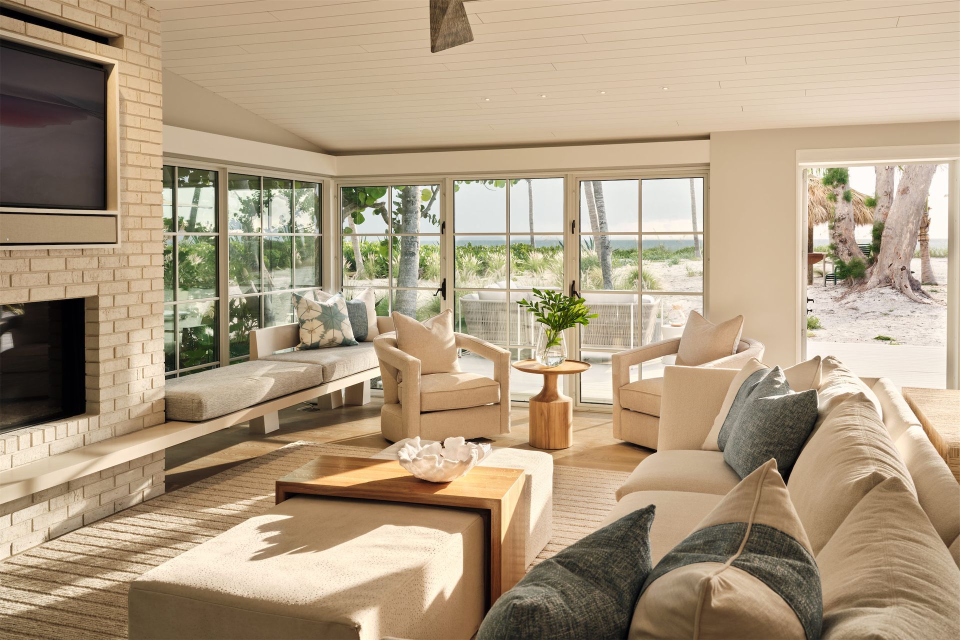 a sunny living room with a couch and chairs and a fireplace