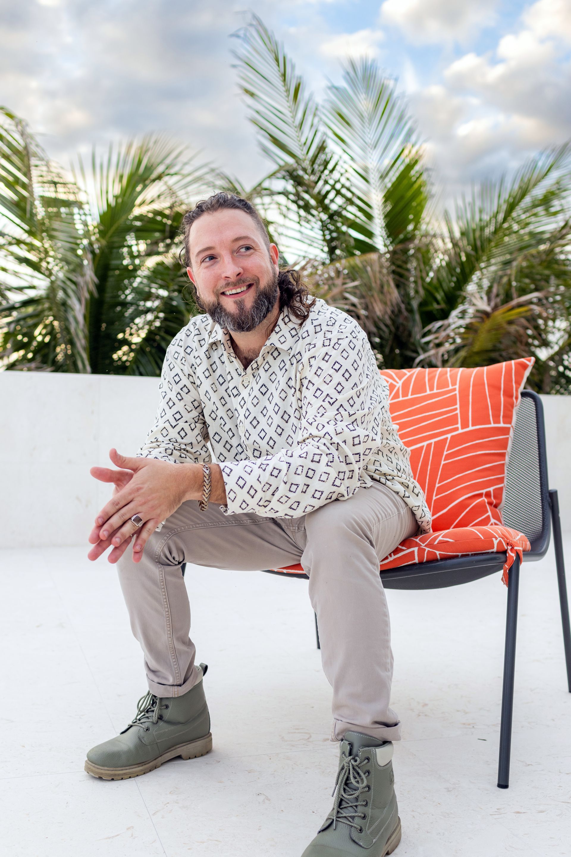 A man is sitting on a chair with a pillow on it.