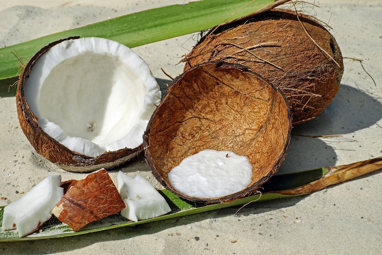 coconuts sitting on a sandy surface and one of them has been cut in half
