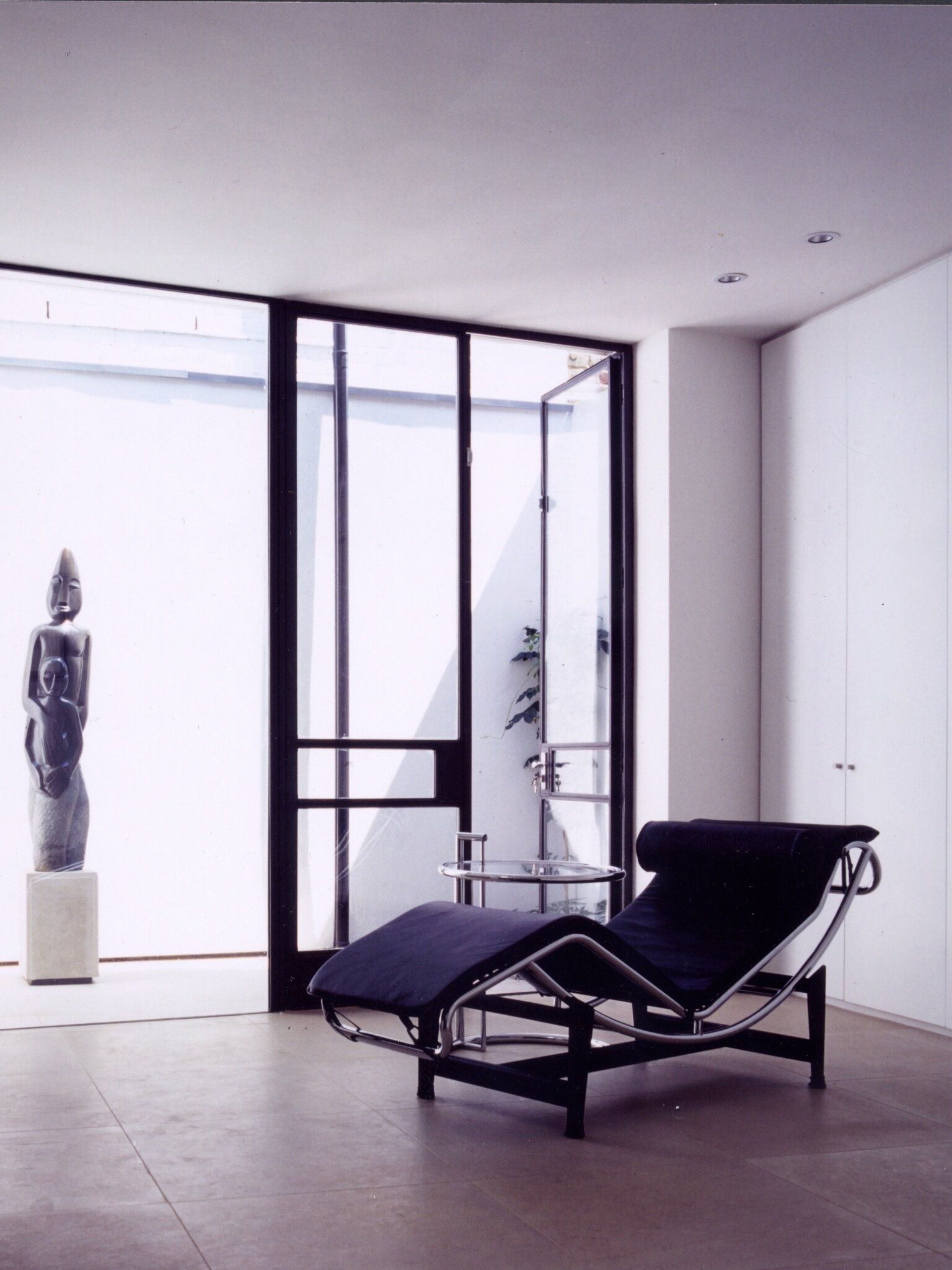 a black chaise lounge in a room with a statue in the background