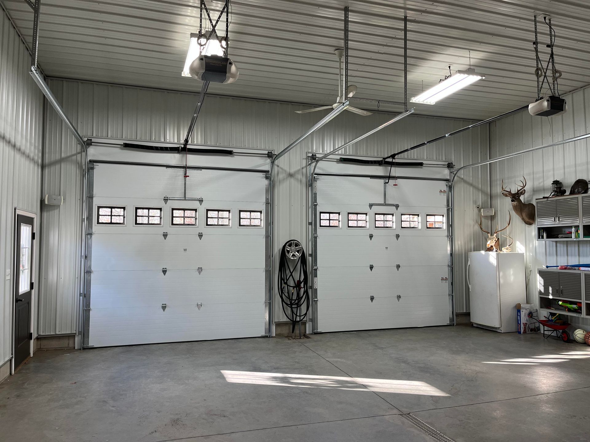 A large garage with two garage doors and a ceiling fan.