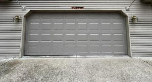A large gray garage door is sitting on the side of a house.