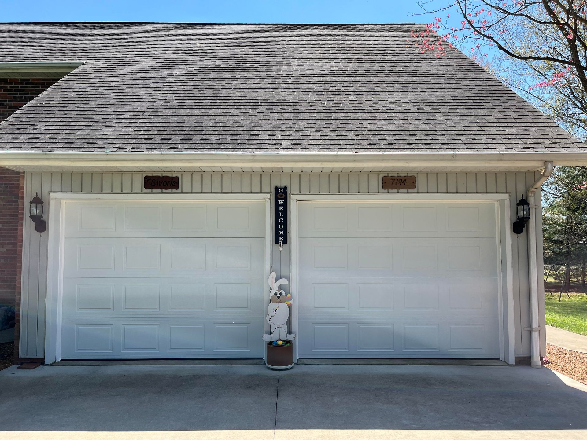 There are two white garage doors on the side of a house.