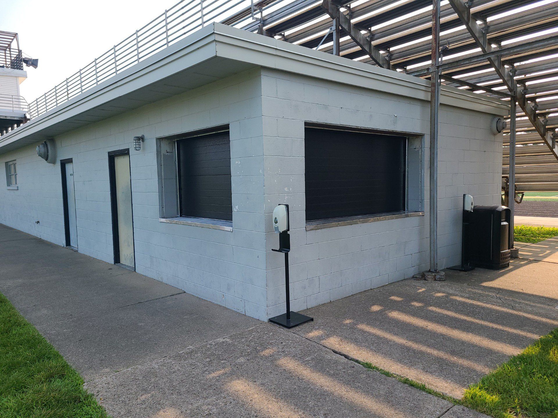A white building with a hand sanitizer dispenser on the side of it.
