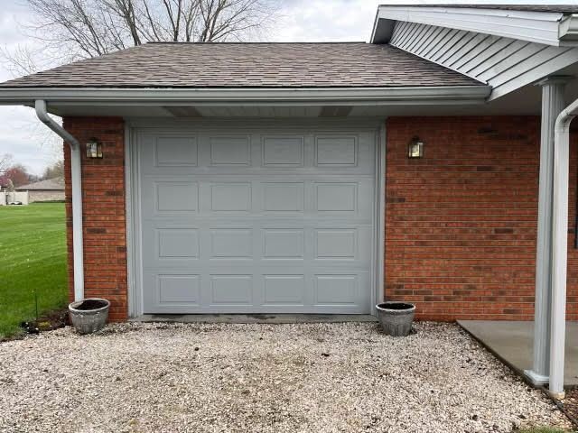 A brick house with a garage door and a gravel driveway.