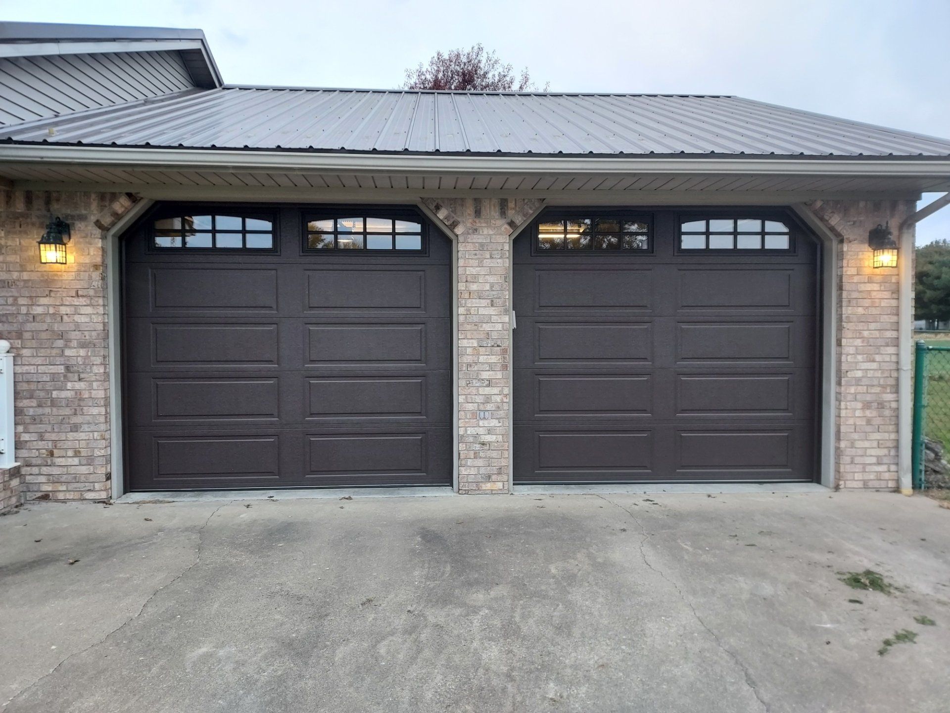 There are two garage doors on the side of a house.