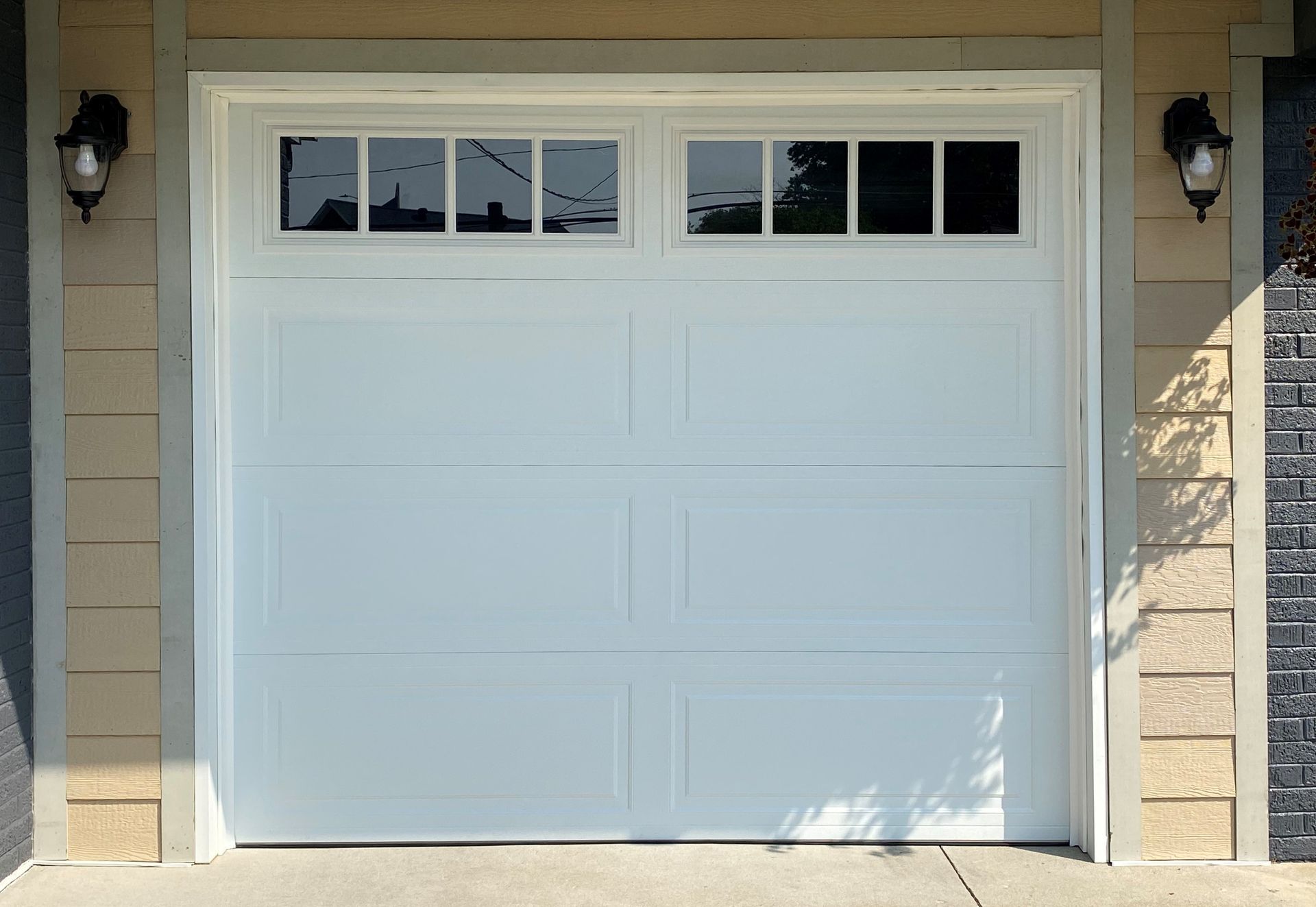 A white garage door with a window on the side of a house.