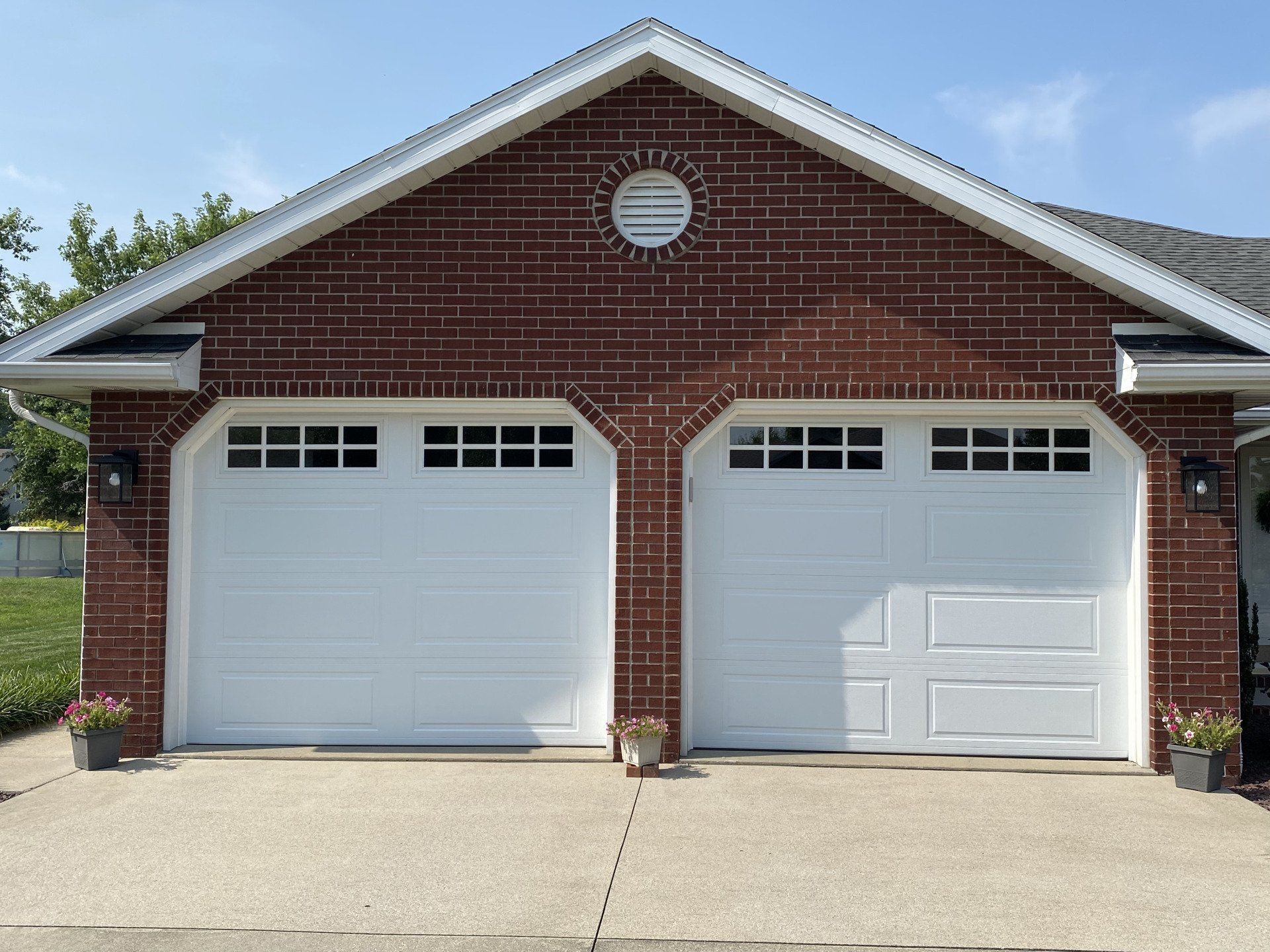 A red brick garage with two white garage doors
