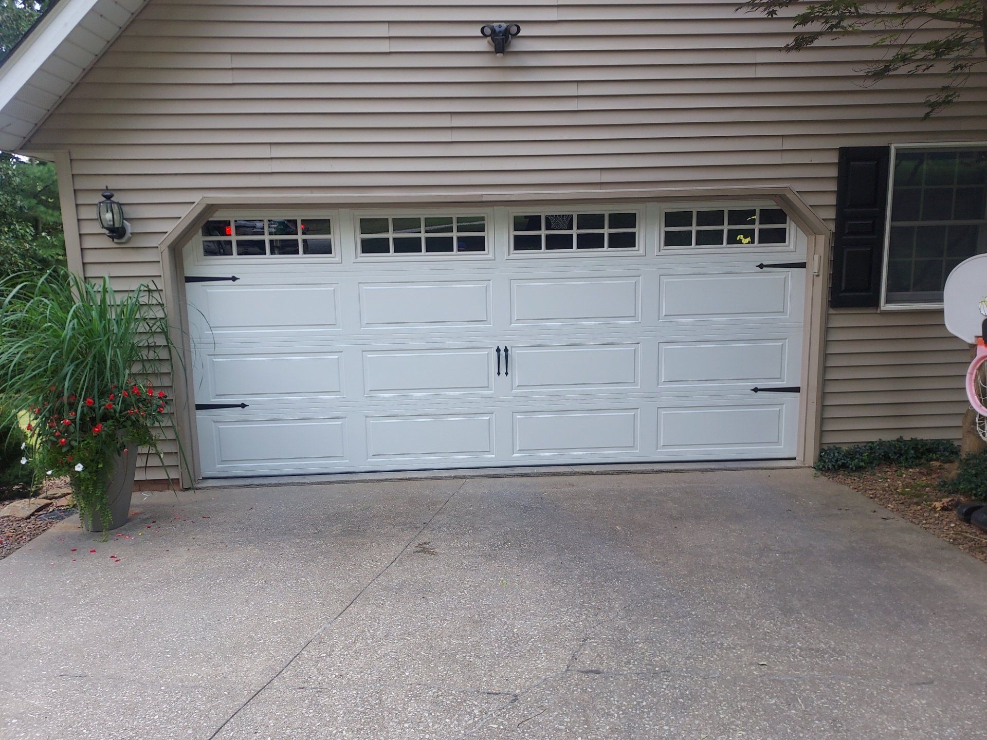 A white garage door is sitting in front of a house.