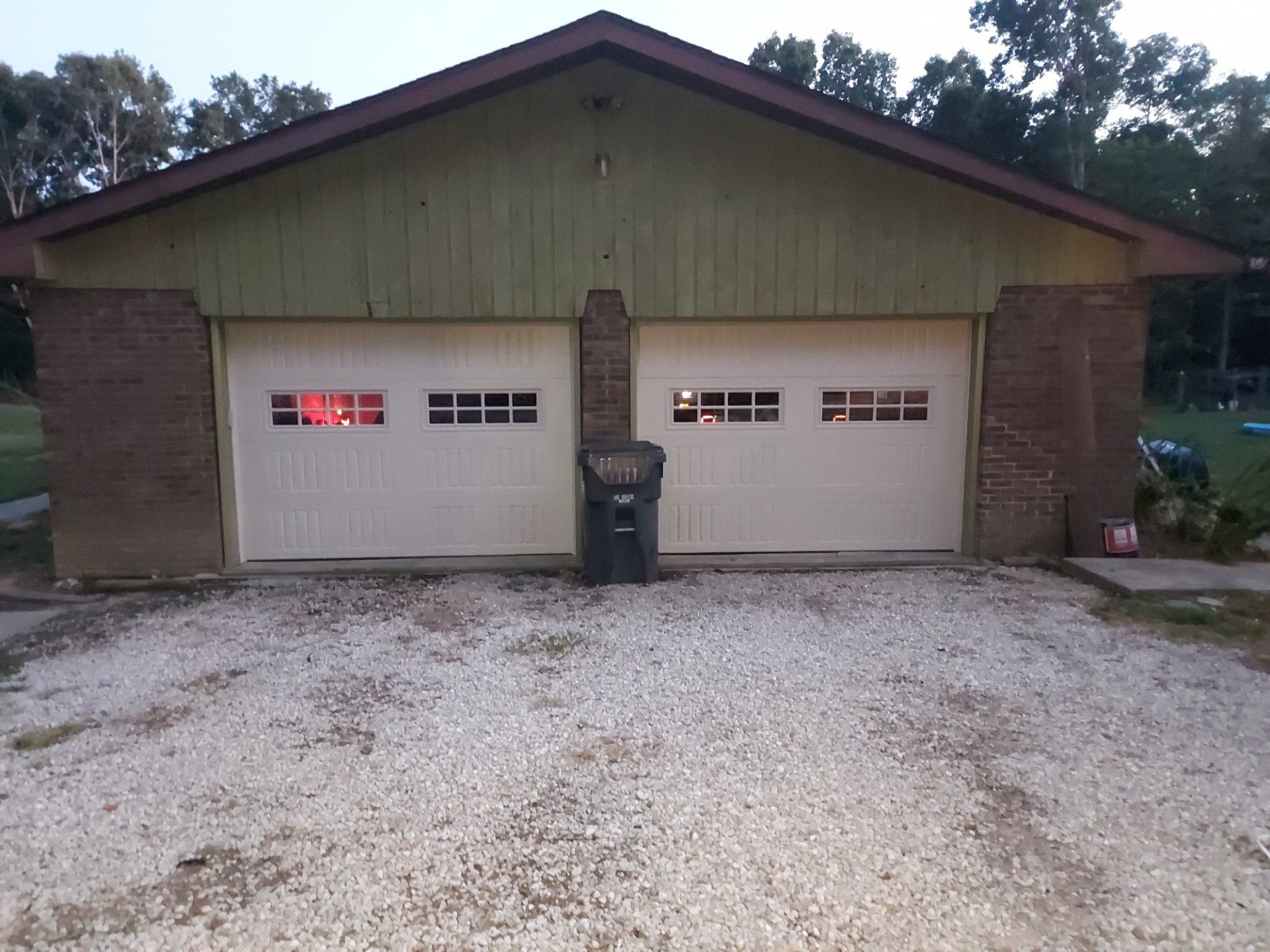 A garage with a trash can in front of it